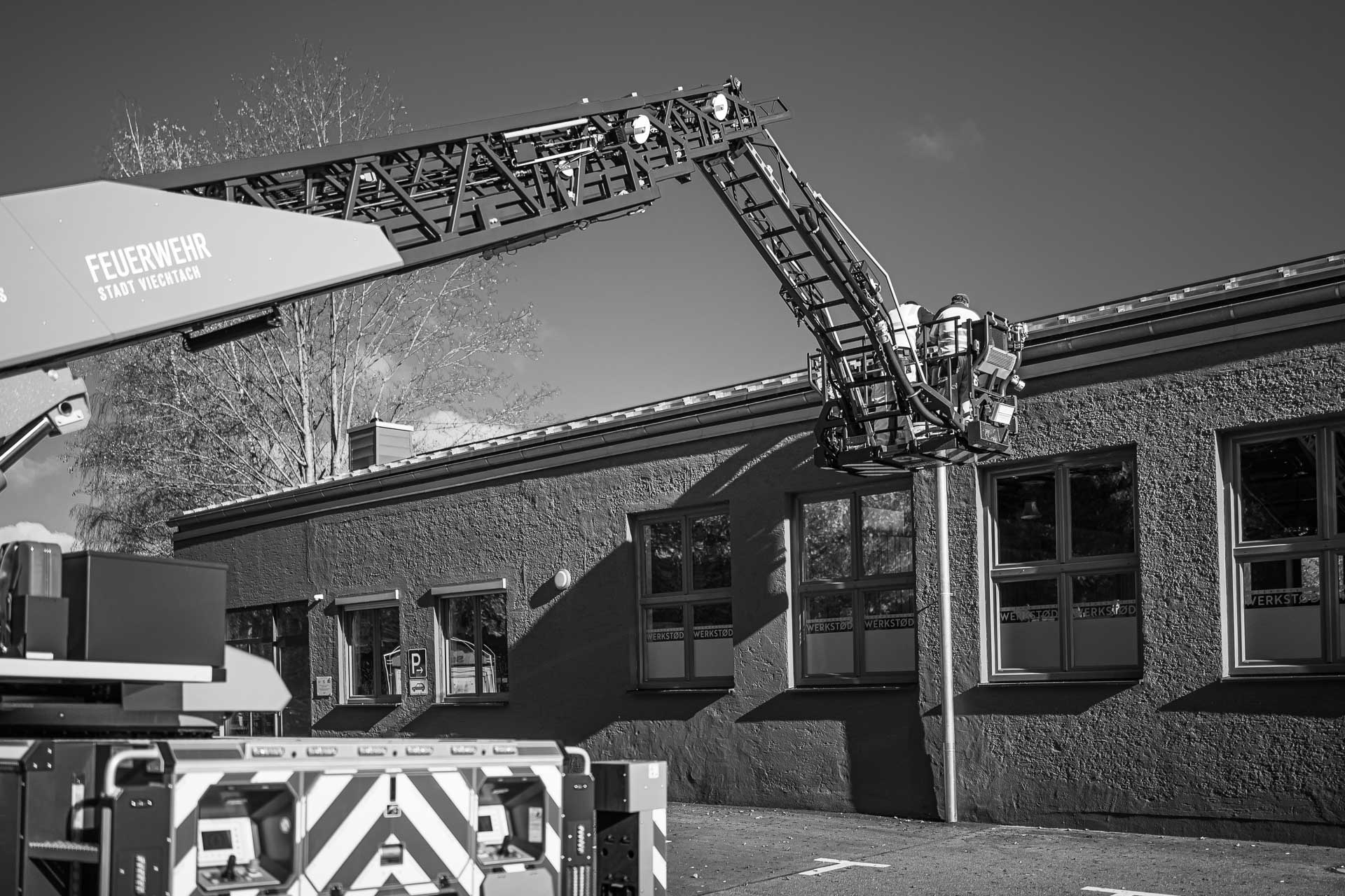 zwei Arbeiter im Feuerwehrkran an einer Dachrinne