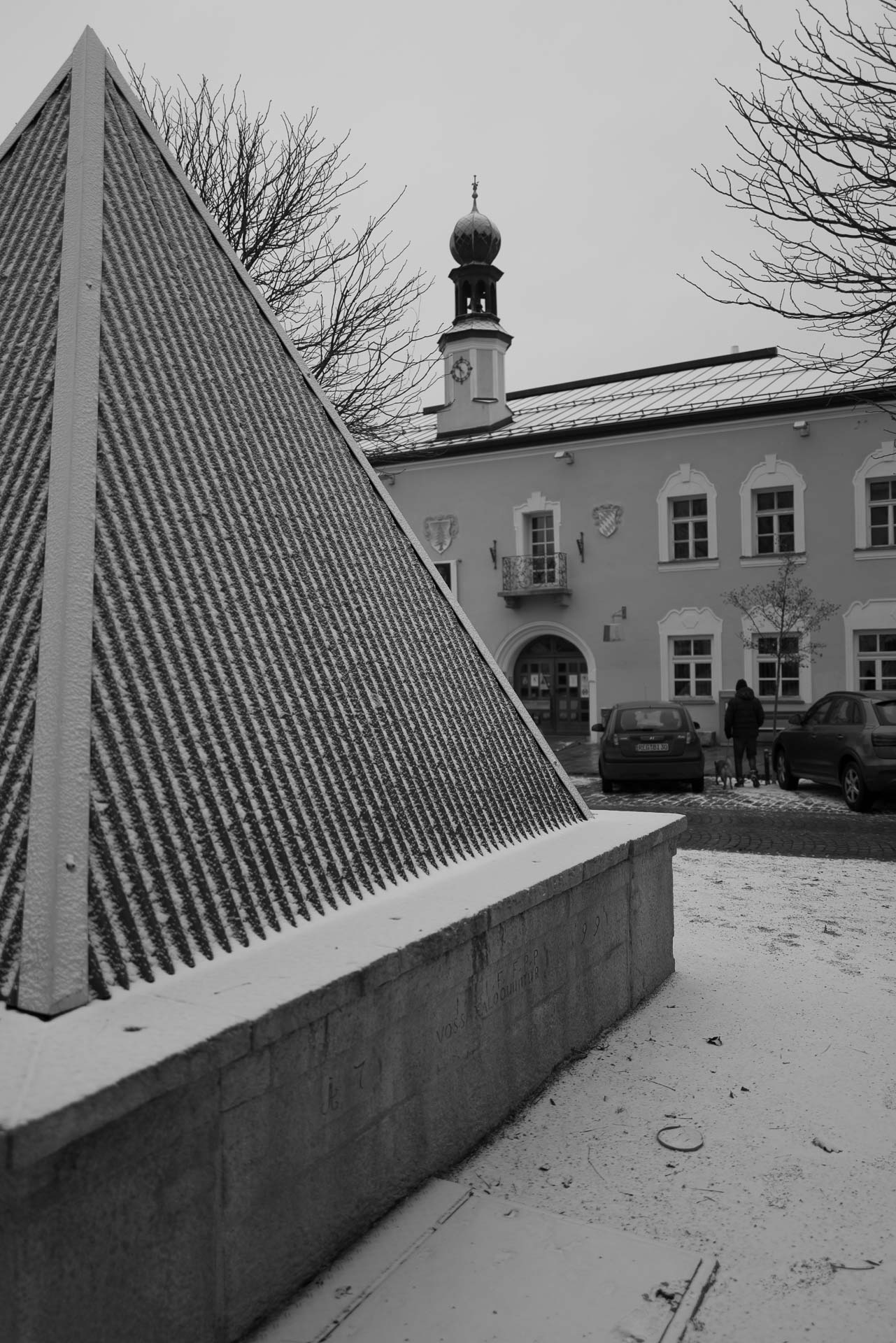 Neuschnee am Stadtplatz mit Spaziergänger mit Hund