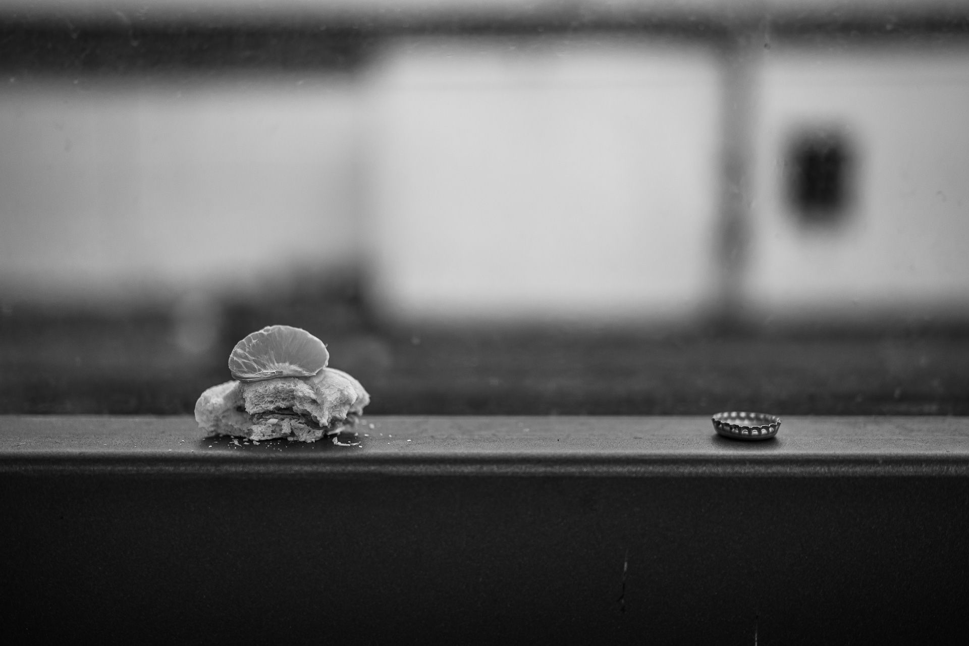 Stilleben angebissenes Brötchen mit Mandarinenspalte und Kronkorken seitlich daneben